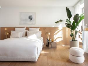 a white bedroom with a white bed and a plant at The Roc Club in Athens