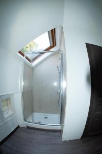 La salle de bains est pourvue d'une douche en verre et d'une fenêtre. dans l'établissement SUITE dans VILLA MEXICAINE, à Jausiers