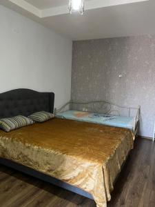 a bedroom with a bed with a gold blanket on it at 3 minutes walk from the sea in Batumi