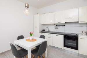 een witte keuken met een witte tafel en stoelen bij Ocean Pearl in Duće