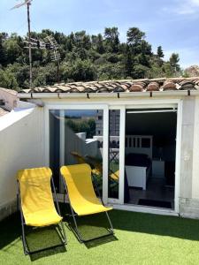 Dos sillas amarillas sentadas en el césped de un patio. en Duplex rare avec terrasse vue à 360 Théâtre, en Orange