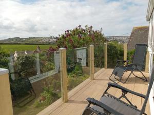 a deck with chairs and a view of the countryside at Curlews Cottage - House with 3 bedrooms and garden - walking distance to the beach in Perranporth