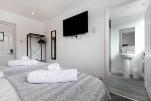 a white bedroom with two beds and a flat screen tv at The Nook - Self Serviced Accommodation in St Ives