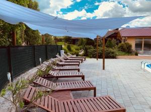 a row of wooden benches with a white canopy at Villa Rubcic in Rakovica