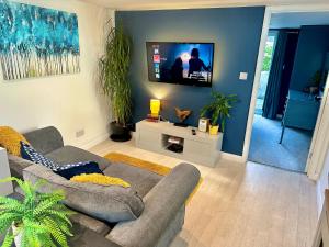 uma sala de estar com um sofá e uma televisão de ecrã plano em A Hidden Gem With Private Hot Tub and Garden - Netflix - Fast Wifi - Free Parking em Bournemouth