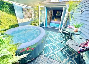 a jacuzzi tub on a porch with a table at A Hidden Gem With Private Hot Tub and Garden - Netflix - Fast Wifi - Free Parking in Bournemouth