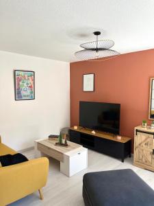 een woonkamer met een flatscreen-tv en een bank bij Un,Deux,Trois...Soleil in Le Pradet