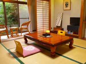 sala de estar con mesa de madera y sillas en Takarabune Onsen Yumoto Kotobuki, en Takashima