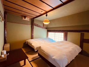 a bedroom with a white bed and a window at 古民家ホテル 結 YUWAI in Hakuba