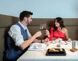 een man en vrouw aan een tafel met wijnglazen bij Hotel Pozzamanigoni in Selva di Val Gardena