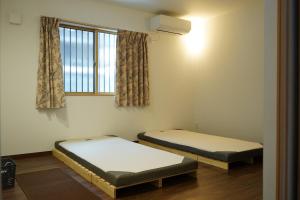 dwa łóżka w pokoju z oknem w obiekcie ミロクハウス w mieście Daisen