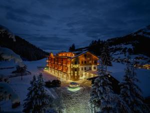 un grand bâtiment dans la neige la nuit dans l'établissement Hotel Pozzamanigoni, à Selva di Val Gardena