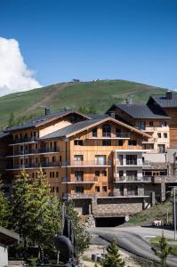 een groot appartementencomplex met een heuvel op de achtergrond bij Résidence Daria-I Nor by les Etincelles in L'Alpe-d'Huez