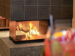 a fire in a fireplace with a glass of soda at Hotel Pozzamanigoni in Selva di Val Gardena