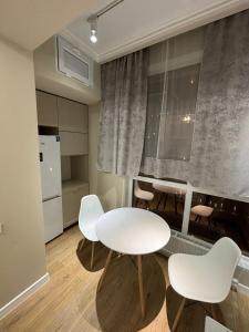 - un salon avec une table et des chaises blanches dans l'établissement Comfort City Apart #1, à (( Gornyy Gigant ))
