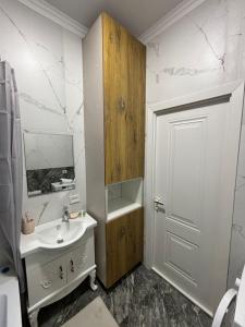La salle de bains est pourvue d'un lavabo, d'un miroir et d'une porte. dans l'établissement Comfort City Apart #1, à (( Gornyy Gigant ))