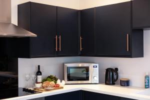 a kitchen with black cabinets and a microwave at The Nook in St Ives
