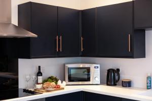 a kitchen with black cabinets and a microwave at The Nook - Self Serviced Accommodation in St Ives