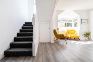 a living room with stairs and yellow chairs at The Nook - Self Serviced Accommodation in St Ives