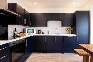 a kitchen with navy blue cabinets and white counter tops at The Nook - Self Serviced Accommodation in St Ives