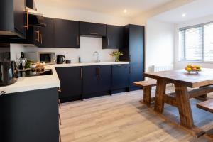 a kitchen with black cabinets and a wooden table at The Nook - Self Serviced Accommodation in St Ives