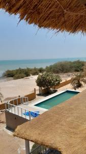 a resort with a swimming pool next to a beach at la villa sur la plage in Palmarin