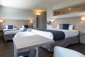 a hotel room with two beds and a table at The Originals Access, Hôtel Millau Sud in LʼHospitalet-du-Larzac