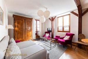 sala de estar con sofá blanco y sillas moradas en Au Bonheur des Anges Appartement 2 chambres avec terrasse, en Colmar