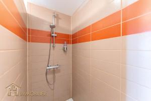 La salle de bains est pourvue d'une douche et de carrelage orange et blanc. dans l'établissement Au Bonheur des Anges Appartement 2 chambres avec terrasse, à Colmar