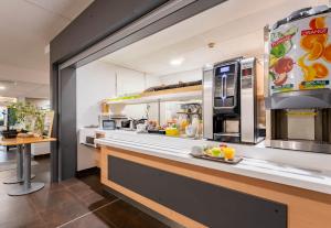 a large kitchen with a counter with food on it at B&B HOTEL Valenciennes Sud in Valenciennes