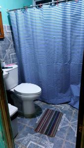 baño con aseo y cortina de ducha azul en El Almendro, en La Cruz