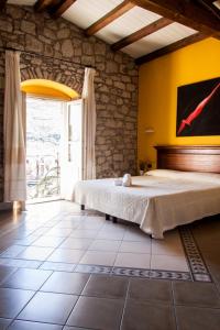 a bedroom with a bed and a large window at Corte Fiorita Albergo Diffuso in Bosa