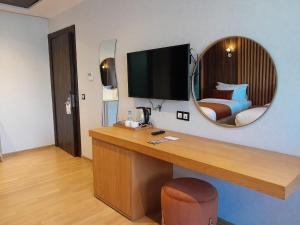 a room with a desk with a television and a bed at Razane Hôtel in Kenitra