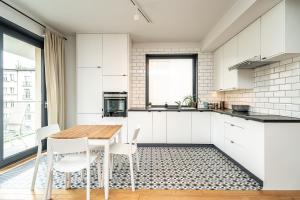 una cocina con armarios blancos y una mesa y sillas de madera. en RentPlanet - Kamienica Retmana en Cracovia