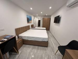 a bedroom with two beds and a desk and a tv at La Bella Guesthouse in St. Julianʼs