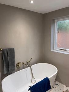 een badkamer met een wit bad en een raam bij Stunning 3 bedroom house sleeps up to 6 in Norwood