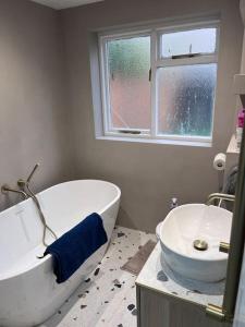 een witte badkamer met een bad en een wastafel bij Stunning 3 bedroom house sleeps up to 6 in Norwood
