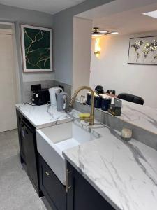 - une cuisine avec des comptoirs en marbre blanc et un évier dans l'établissement Stunning 3 bedroom house sleeps up to 6, à Norwood