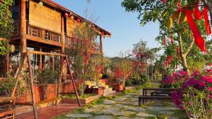 a building with a garden with a bench and flowers at Nhà gỗ Homestay in Bao Loc