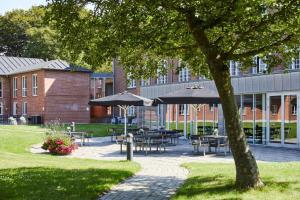 a park with tables and umbrellas in front of a building at Danhostel Esbjerg in Esbjerg