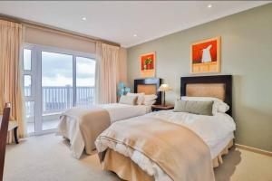 a large bedroom with two beds and a balcony at Pinnacle Point Penthouse 14-5 in Mossel Bay +57 photos