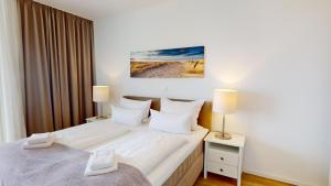 a bedroom with a large white bed with two lamps at Südkap G-06 in Pelzerhaken