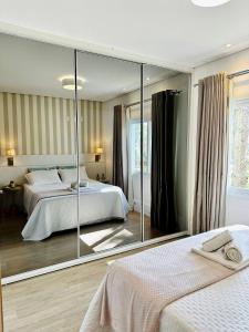 1 dormitorio con 2 camas y un espejo grande en Apto LINDO com lareira, piscina aquecida e jacuzzi en Gramado