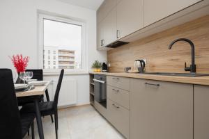 a kitchen with white cabinets and a table and a window at Stylish Apartment with Parking Warsaw Ursus by Rent like home in Warsaw