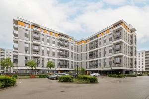 a large white building with cars parked in a parking lot at Stylish Apartment with Parking Warsaw Ursus by Rent like home in Warsaw