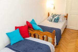two beds with colorful pillows in a room at Apartment Sea Organ in Zadar