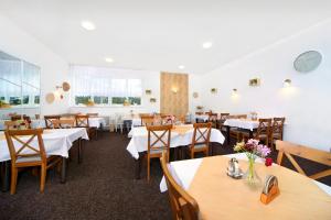 uma sala de jantar com mesas brancas e cadeiras de madeira em Hotel Lenka em Spindleruv Mlyn
