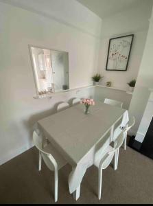 een witte eettafel met stoelen en een vaas met bloemen bij Spacious Ashley Cross Flat in Parkstone