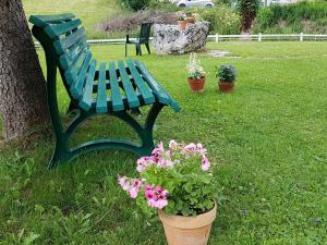 un banco verde sentado junto a un árbol y flores en Dvacances Résidence les tavaillons, en Mijoux