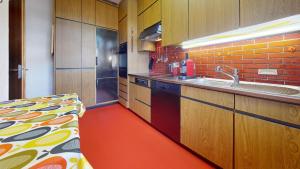 - une cuisine avec des placards en bois et un sol rouge dans l'établissement Unique Serviced Living @ Wettstein Turnerstrasse, à Bâle
